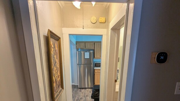 A hallway leading to a kitchen with a stainless steel refrigerator, wooden cabinets, and a tiled backsplash. - MinCo Properties WV, Carswell Hollow Overlook  (Kimball)