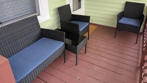 A porch with two wicker chairs and a sofa, a door, and a window with blinds. - MinCo Properties WV, Carswell Hollow Overlook  (Kimball)