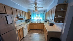 A kitchen with wooden cabinets, a refrigerator, a stove, and a ceiling fan. - MinCo Properties WV, Carswell Hollow Overlook  (Kimball)