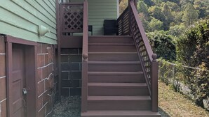 A wooden staircase leading to a covered porch with a view of a forested hillside. - MinCo Properties WV, Carswell Hollow Overlook  (Kimball)
