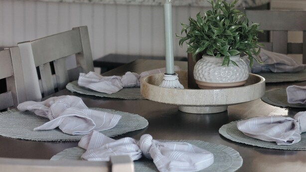 A kitchen with a dining table set for four, a refrigerator, and a window with blinds.