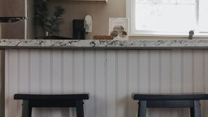 A kitchen with white cabinets, a stainless steel refrigerator, and a window with a view.