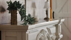 A fireplace with a decorative mantel, a television mounted above it, and a potted plant on the mantel.