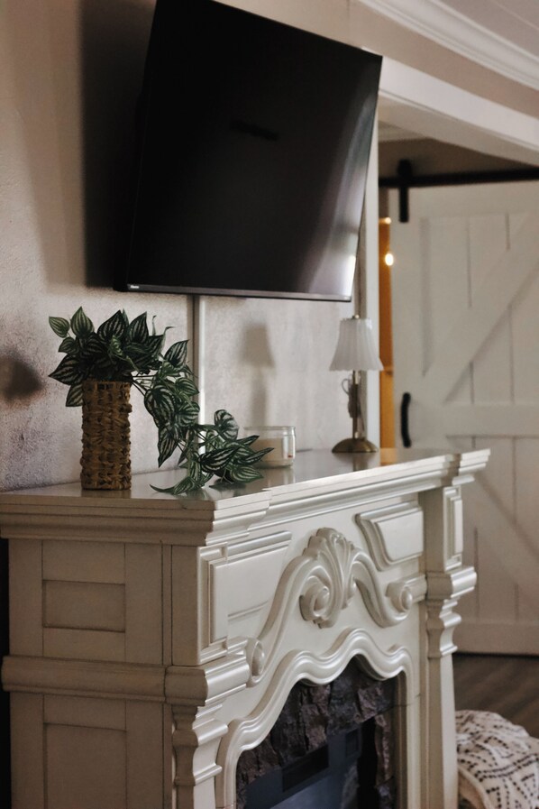 A fireplace with a decorative mantel, a television mounted above it, and a potted plant on the mantel. - 3-bedroom Home
Royal Haven Vacation Destination (Murphysboro)