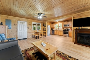Interior de una cabaña de madera con comedor, cocina y sala de estar.