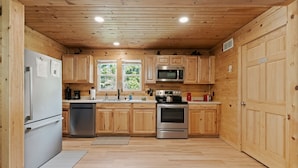 Une cuisine compacte avec des meubles en bois, un réfrigérateur en acier inoxydable, un four à micro-ondes et un four traditionnel.