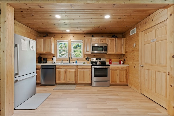 Una cocina funcional con armarios de madera, un refrigerador de acero inoxidable, un microondas y un horno.