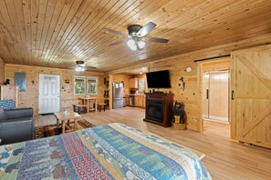L’intérieur d’une cabane en rondins comprend un grand lit, un coin repas, une cuisine et une cheminée.