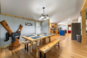 Una habitación amplia con una mesa de madera, bancos y una escultura de madera original.