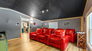 Una habitación con un sofá de cuero rojo, suelo de madera, techo negro y una ventana.