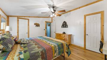 Un dormitorio con cama, cómoda, ventilador de techo y puerta.