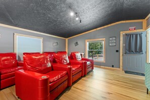 Een kamer met een rode leren zithoek, houten vloeren, een grijs plafond en een deur met de tekst 'Emergency Exit Only'.