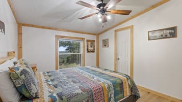 A bedroom with a bed, a ceiling fan, a window, and a door.