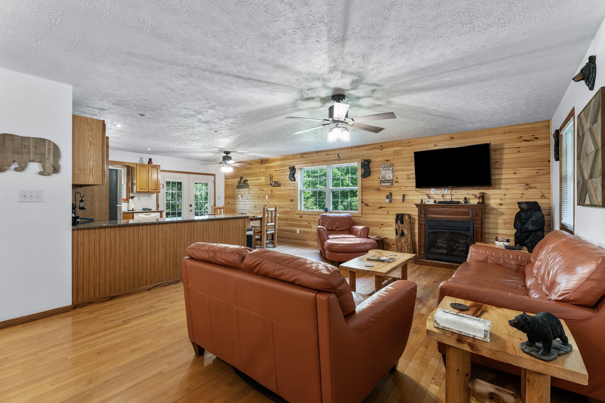 A spacious living area with a fireplace, leather sofas, and a wooden dining table.