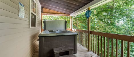 A wooden deck with a hot tub and a small step leading to it.