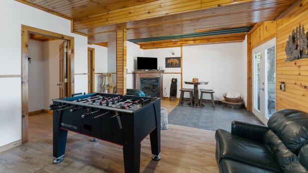 A cozy room with a foosball table, a fireplace, a television, and a leather couch. - Bearadise Ridge | Hocking Hills, Game Room, Arcade (Laurelville)