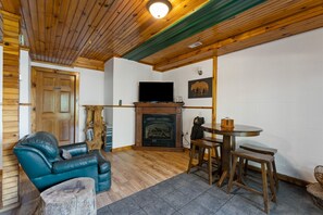 Une pièce chaleureuse avec une cheminée, un téléviseur, un plafond en bois et un canapé en cuir.