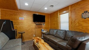 A room with a wooden wall, a television mounted on the wall, a brown leather couch, a small wooden table, and a sign that says "Gaming Keep Out". - Beartastic Outlook | Hocking Hills, Hot Tub (Rockbridge)