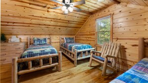 A cabin with two wooden beds, a rocking chair, and a ceiling fan. - Beartastic Outlook | Hocking Hills, Hot Tub (Rockbridge)