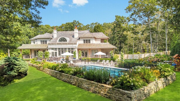 A large house with a swimming pool, surrounded by lush greenery and trees. - Spacious & chic Southampton estate with heated pool, fire pit &... (Southampton)