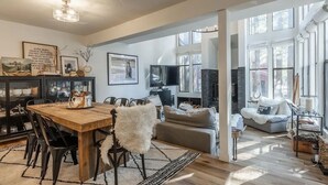 A spacious living area with a wooden dining table, comfortable seating, and a fireplace. - Bright, beautiful condo in the heart of Mammoth, near shuttle, shops, ski & golf (Mammoth Lakes)