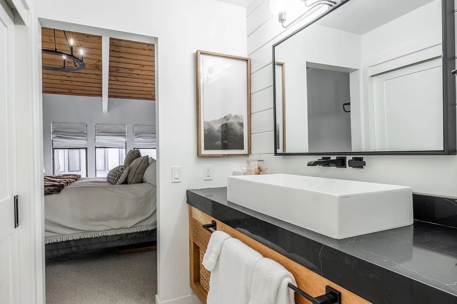 Un baño moderno con un lavamanos grande de color blanco, un mueble de tocador de madera y un espejo amplio.