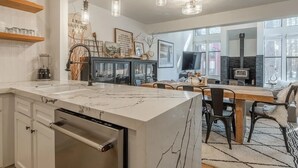 A modern kitchen with a marble island, pendant lights, and a dining area with a fireplace. - Bright, beautiful condo in the heart of Mammoth, near shuttle, shops, ski & golf (Mammoth Lakes)