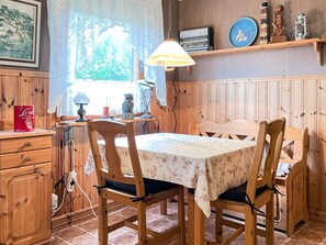 A dining area with a wooden table and chairs, a lamp, and a shelf with decorative items. - 4 Person Holiday Home in Smedstorp (Tomelilla)