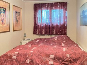 A bedroom with a bed, a nightstand, a lamp, and curtains. - 4 Person Holiday Home in Smedstorp (Tomelilla)