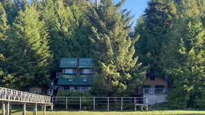 Une propriété au bord du lac, dotée d’une terrasse en bois, d’un petit quai et d’une maison avec un toit végétalisé.