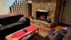 Un salon chaleureux avec une cheminée en pierre, une table basse en bois et un canapé.