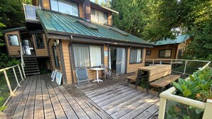 Une terrasse en bois avec une table et des chaises, une petite cuisine extérieure et un patio couvert.