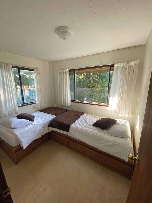 A room with two beds, a ceiling light, and windows with curtains. - Waterfront home located in peaceful Bamfield Inlet with private dock. (Bamfield)