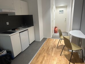 Une cuisine moderne avec des meubles blancs, un plan de travail noir et un plancher en bois. On y trouve un petit coin repas avec une table et deux chaises.