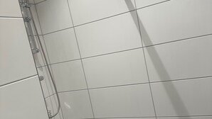 A tiled shower area with a handheld showerhead and a wall-mounted faucet. - Apartment 21 in Sollentuna Stockholm (Sollentuna)