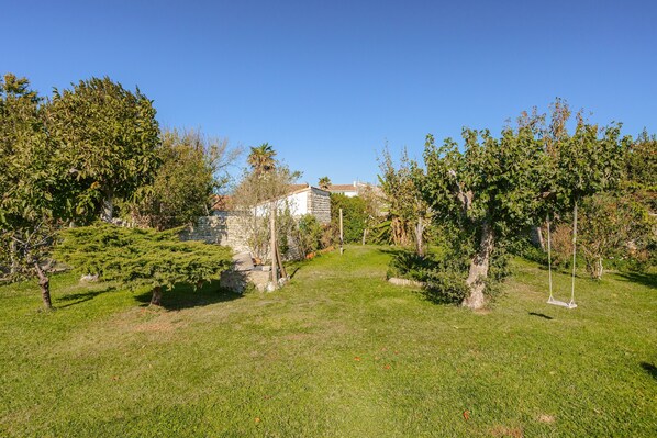 A grassy area with trees and a stone building in the background.