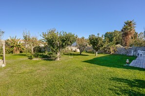A well-maintained grassy area with trees and a stone wall.