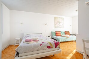 Ein Schlafzimmer mit einem Bett, einem Nachttisch, einem Stuhl und einem Bild an der Wand.