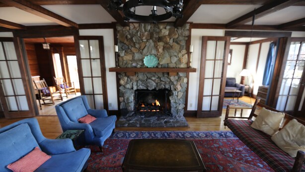 Ein traditionelles Interieur mit Kamin aus Stein, blauen Sofas und einem gemusterten Teppich.