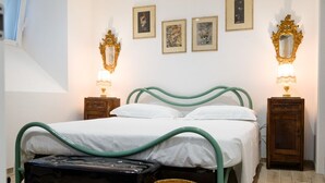 Una camera da letto con un letto, due comodini, una lampada, uno specchio e una cornice appesa al muro.