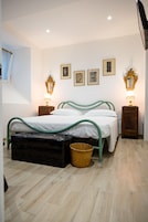 Un dormitorio con una cama, dos mesitas de noche, una lámpara, un espejo y un cuadro colgado en la pared.