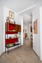 Un pasillo con una estantería de madera, un estante acolchado rojo y una lámpara antigua.