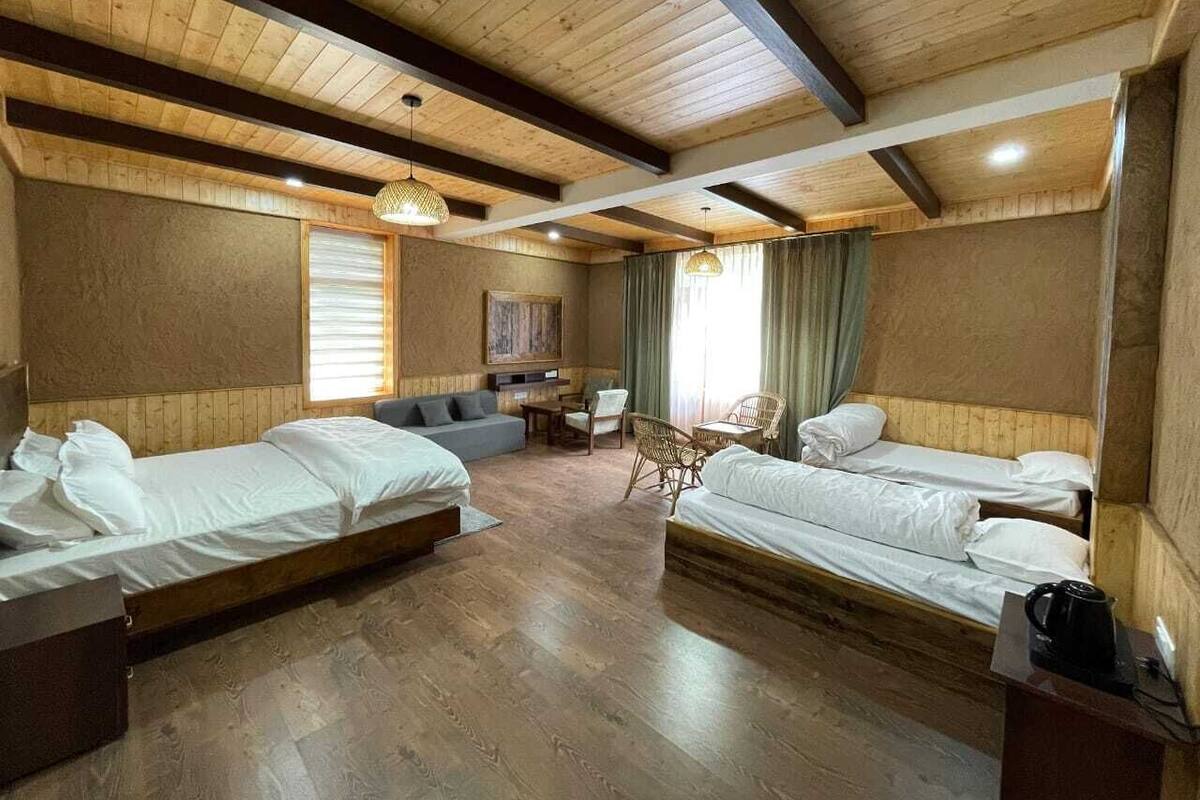 A room with three beds, a sofa, and a table.