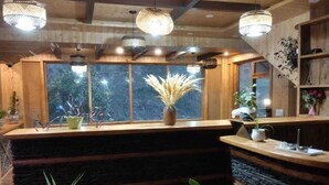 Una zona de recepción con mostrador de madera, ventanas amplias y lámparas colgantes.