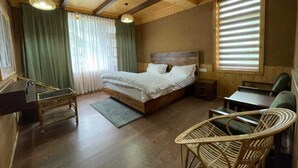 Una habitación con paneles de madera, una cama, un escritorio y sillas de mimbre.