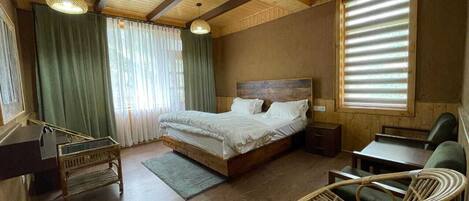 A wooden-paneled room with a bed, a desk, and wicker chairs.