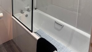 Ett modernt badrum med en duschavdelning med glasväggar och ett fristående badkar.
