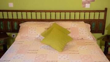 A bed with a quilt, a green pillow, and a wall-mounted light fixture.
