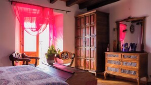 Una camera da letto con un letto, un armadietto in legno, una sedia e un tavolo con una pianta.