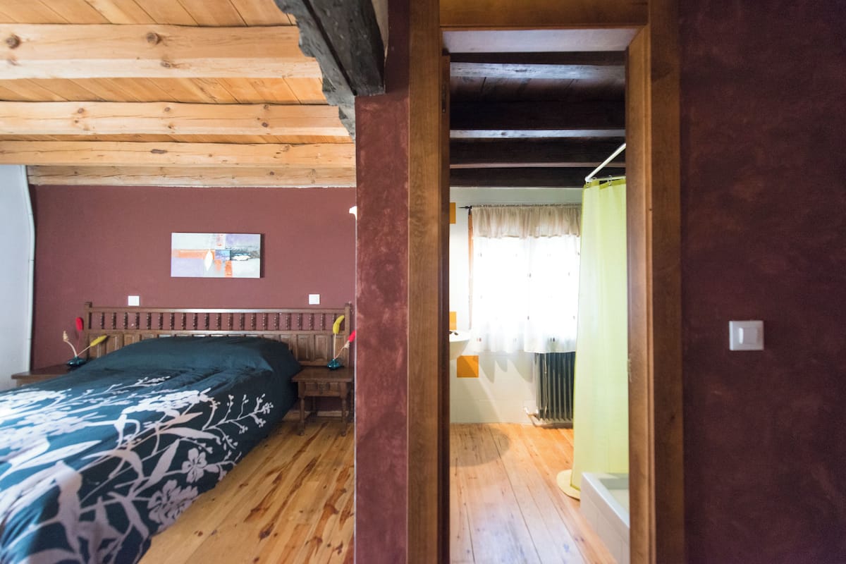 A room with a wooden bed, a small bedside table, and a radiator.